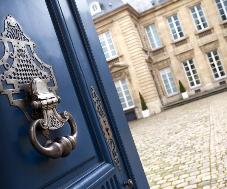 Hôtel particulier vu depuis une porte ancienne, illustrant une stratégie de démembrement de propriété pour optimiser la gestion de patrimoine immobilier.
