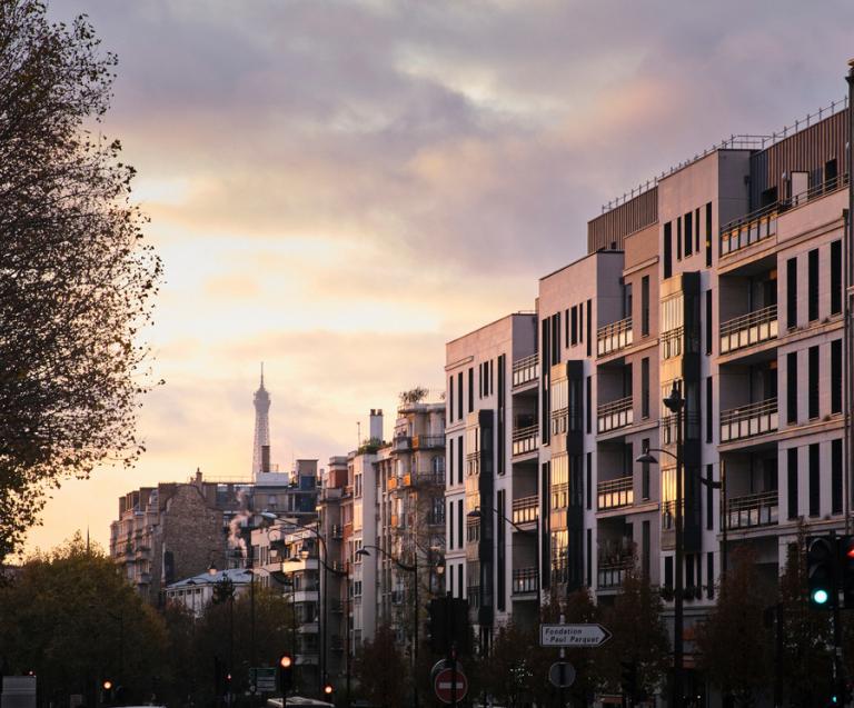 Rue résidentielle au coucher du soleil à Neuilly-sur-Seine, illustrant le dynamisme du marché immobilier local avec vue sur la tour Eiffel.
