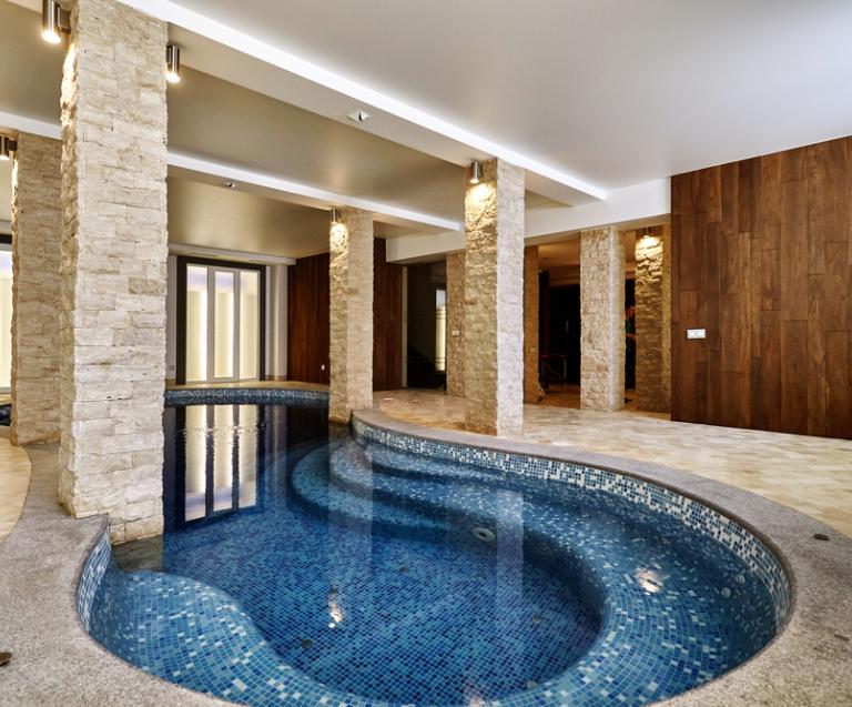  piscine intérieure haut de gamme dans une maison de luxe avec finitions en pierre et bois