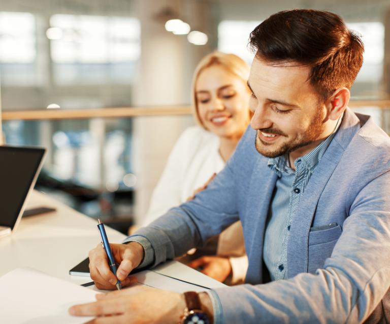 Signature d’un bail d’habitation entre un jeune couple et un professionnel, illustrant les clauses essentielles à insérer dans un contrat de location.