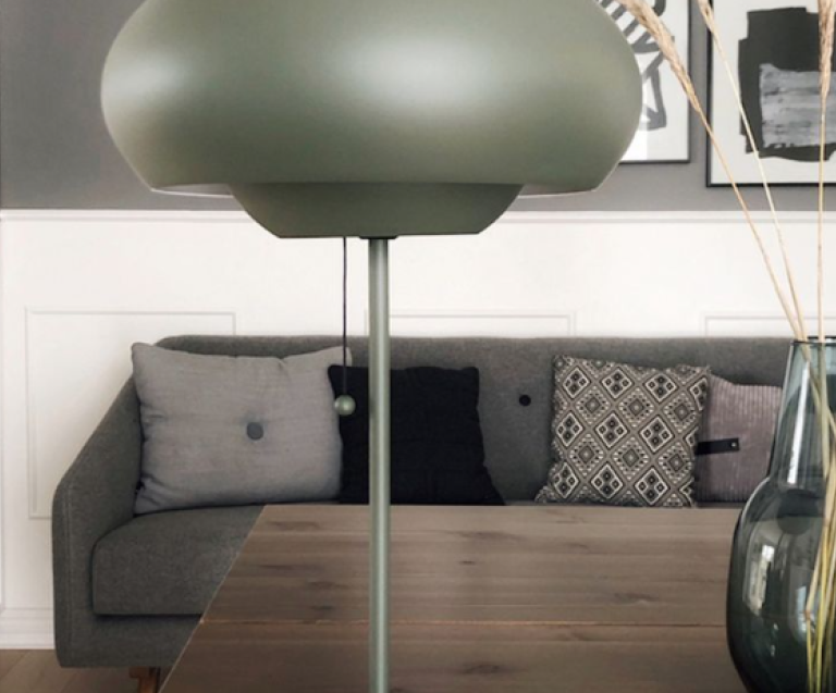 Lampe mushroom design vert kaki posée sur une table en bois dans un salon moderne