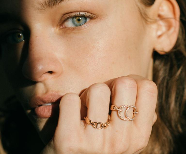 Femme brune aux yeux verts portant des bagues de joaillerie éthique