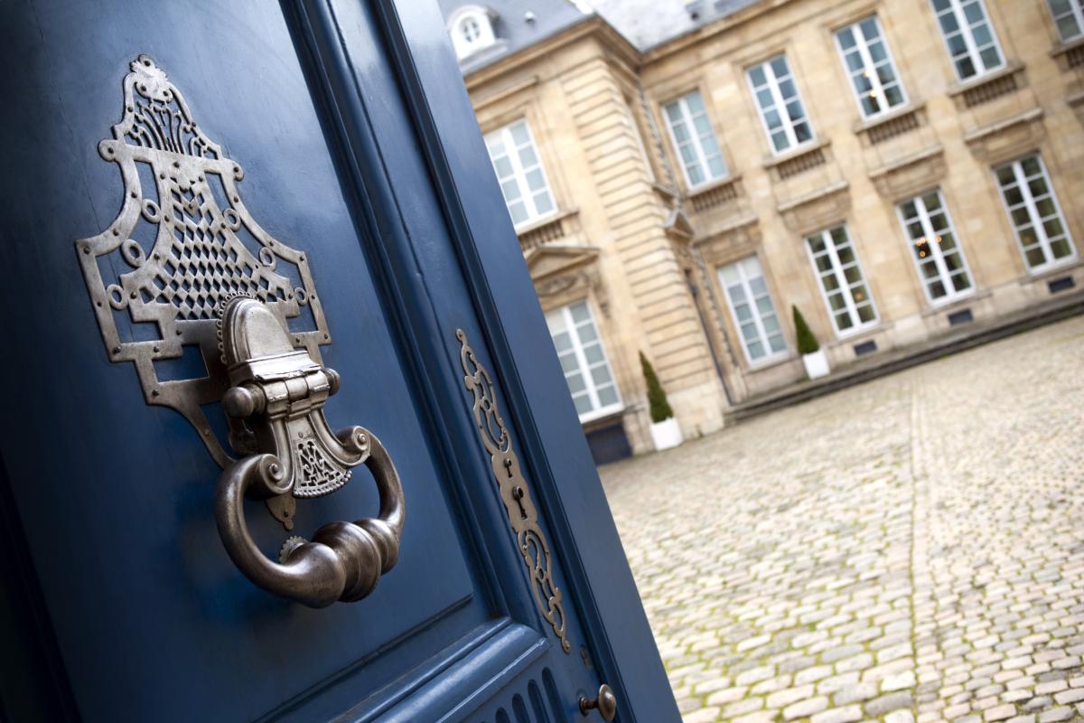 Hôtel particulier vu depuis une porte ancienne, illustrant une stratégie de démembrement de propriété pour optimiser la gestion de patrimoine immobilier.