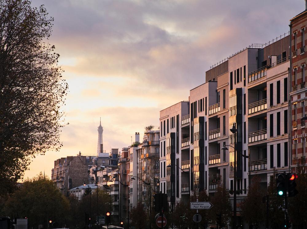 Rue résidentielle au coucher du soleil à Neuilly-sur-Seine, illustrant le dynamisme du marché immobilier local avec vue sur la tour Eiffel.