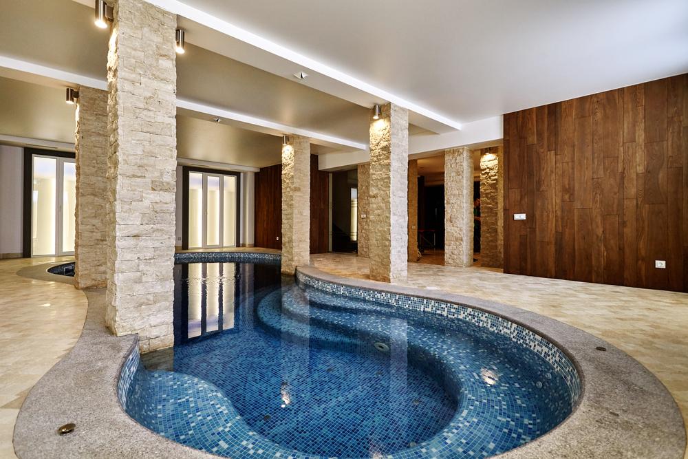 piscine intérieure haut de gamme dans une maison de luxe avec finitions en pierre et bois